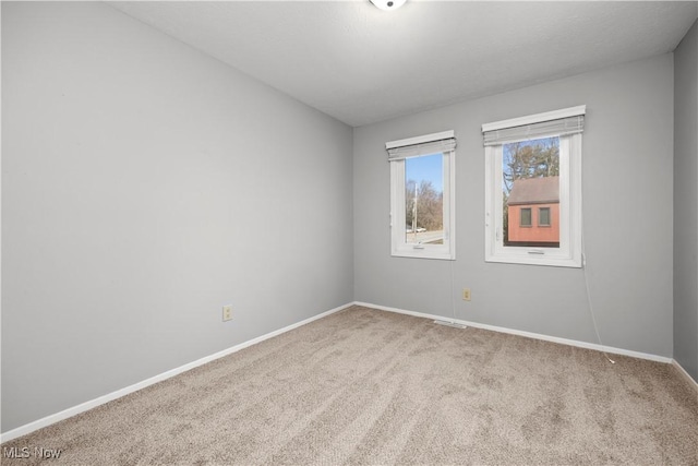 spare room with carpet flooring, visible vents, and baseboards