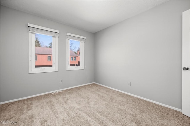 carpeted spare room with visible vents and baseboards