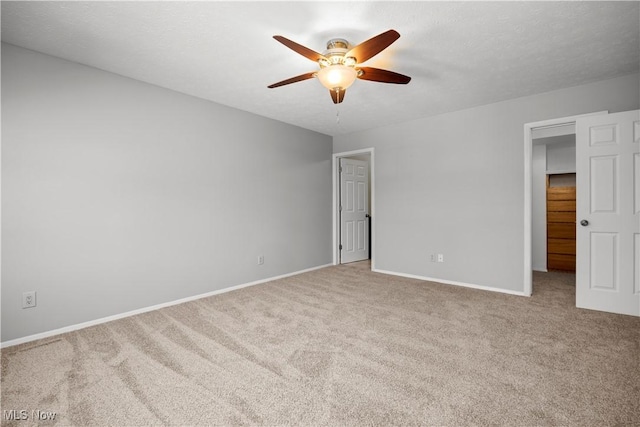 carpeted empty room with baseboards, a textured ceiling, and ceiling fan