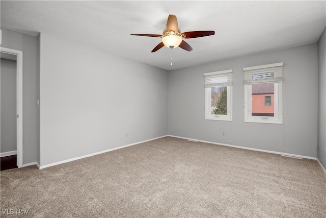 carpeted spare room with baseboards and a ceiling fan