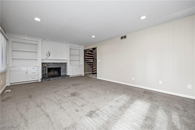 unfurnished living room with carpet flooring, a fireplace, stairs, and built in features