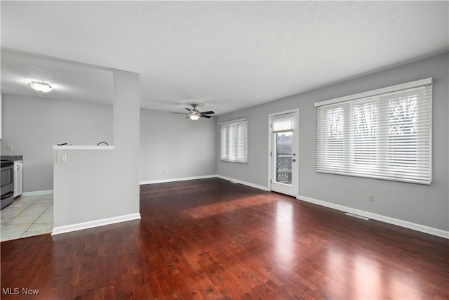 unfurnished living room featuring wood finished floors, a ceiling fan, baseboards, visible vents, and a textured ceiling