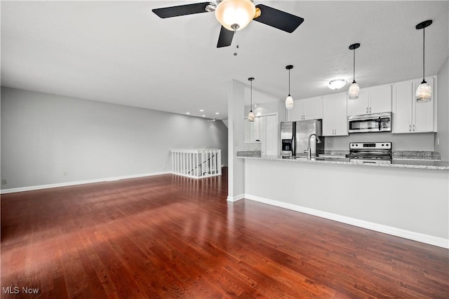 kitchen featuring a ceiling fan, light stone counters, wood finished floors, stainless steel appliances, and baseboards