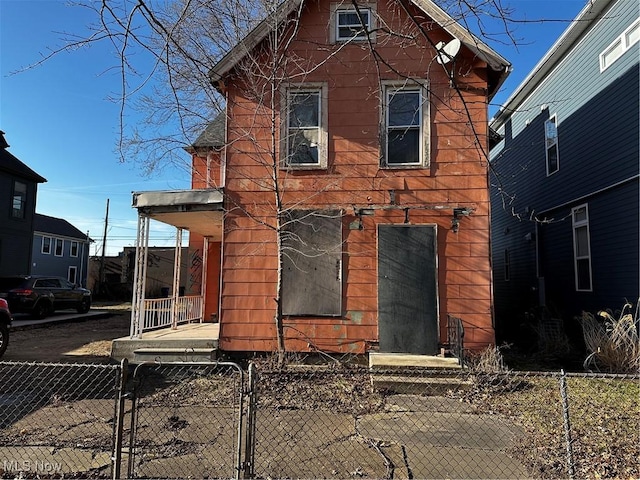 view of front of property with a fenced front yard, a porch, and a gate