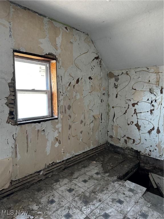 spare room featuring tile patterned floors and vaulted ceiling