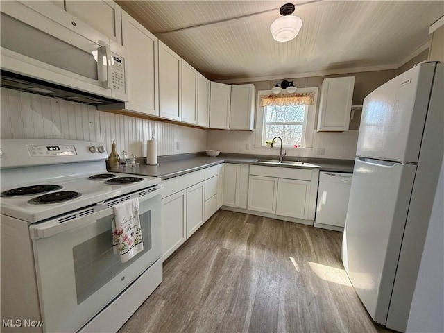 kitchen featuring white appliances, a sink, light wood-style floors, white cabinetry, and dark countertops