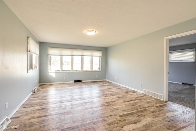 empty room with visible vents, baseboards, and wood finished floors