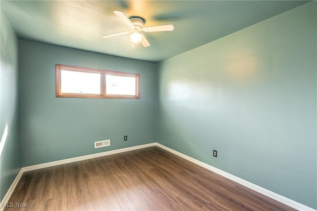 empty room with ceiling fan, visible vents, baseboards, and dark wood finished floors