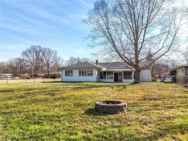 view of front of house featuring fence, a fire pit, a front yard, and a sunroom