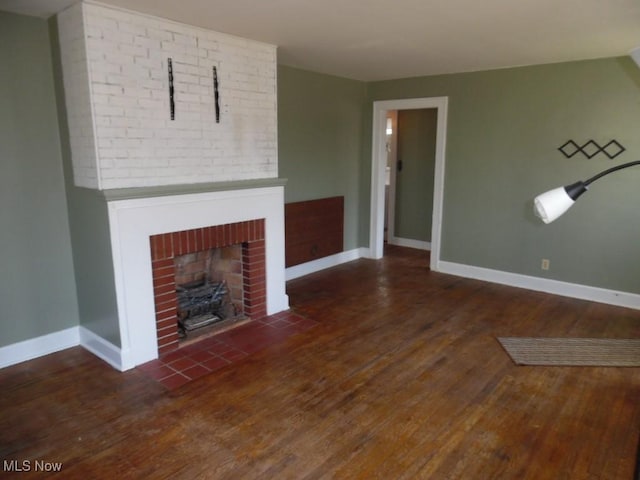 unfurnished living room with a fireplace, baseboards, and wood finished floors