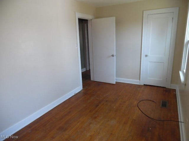 unfurnished bedroom featuring visible vents, baseboards, and wood finished floors