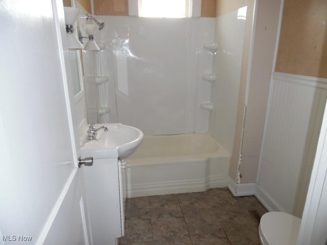 bathroom featuring vanity, bathtub / shower combination, wainscoting, and toilet