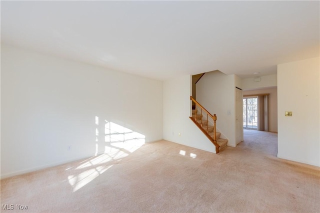 carpeted spare room with stairway