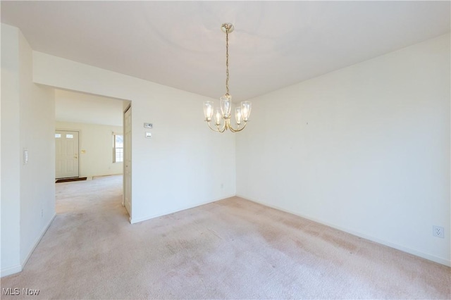 unfurnished room featuring baseboards, light colored carpet, and a chandelier