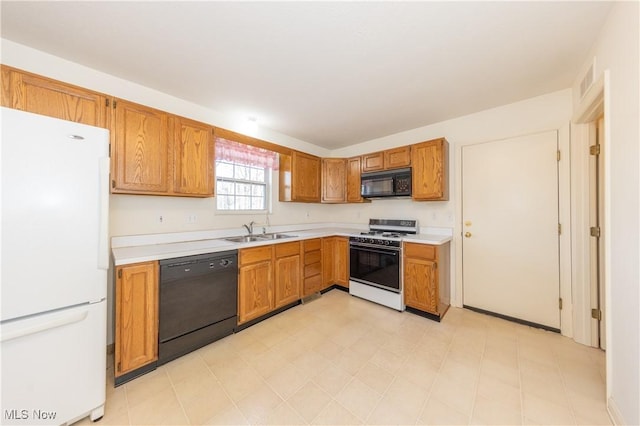 kitchen featuring brown cabinetry, visible vents, a sink, black appliances, and light countertops