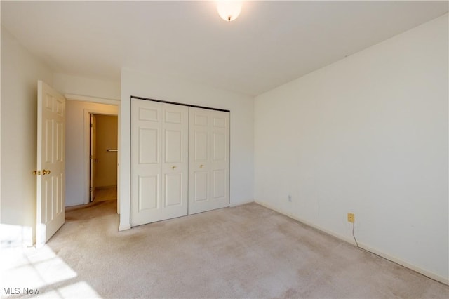 unfurnished bedroom with light colored carpet and a closet