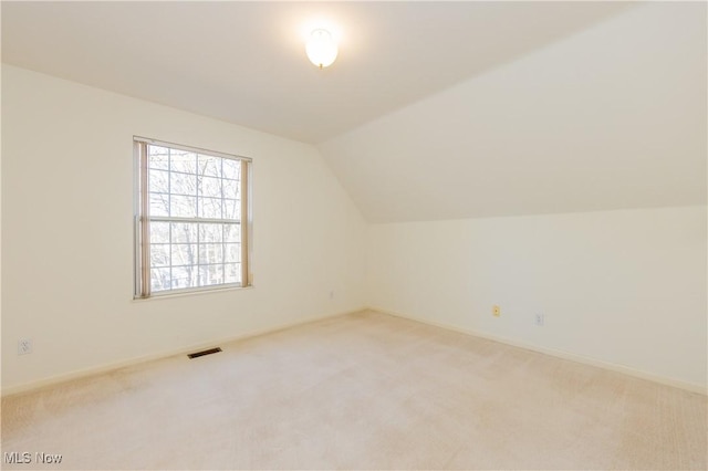 bonus room with baseboards, visible vents, lofted ceiling, and light carpet