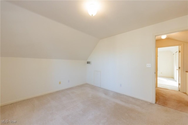 additional living space with visible vents, light carpet, and vaulted ceiling