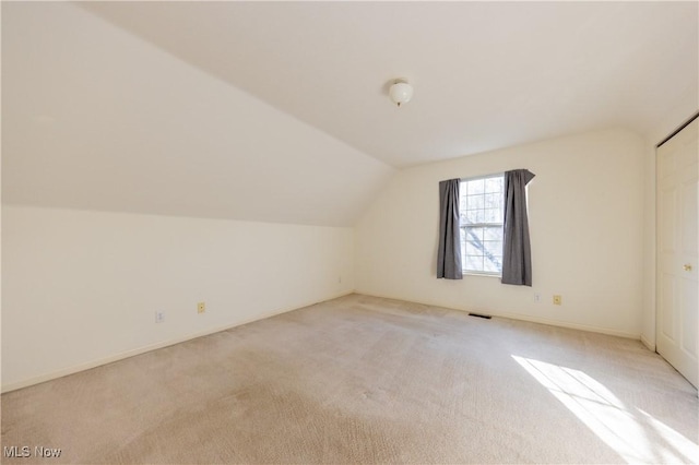 bonus room featuring lofted ceiling, light colored carpet, and visible vents