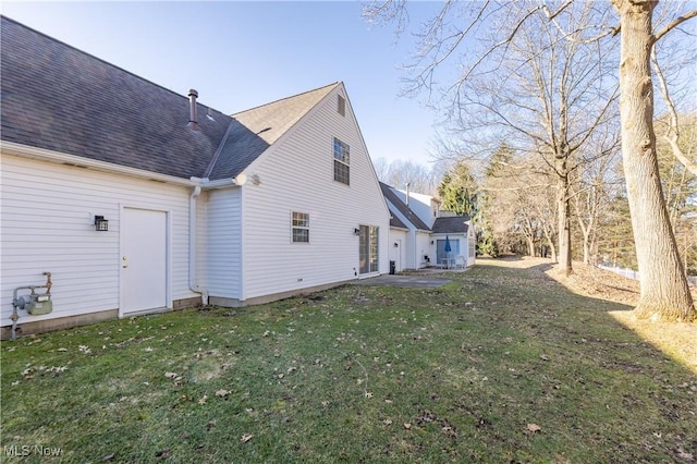 rear view of property featuring a patio area, a yard, and roof with shingles