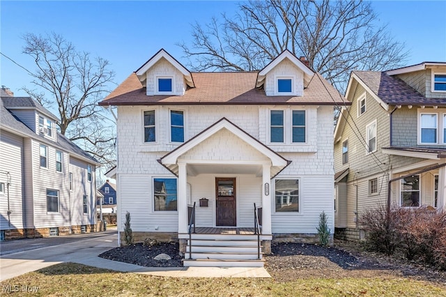 american foursquare style home featuring covered porch, concrete driveway, and roof with shingles