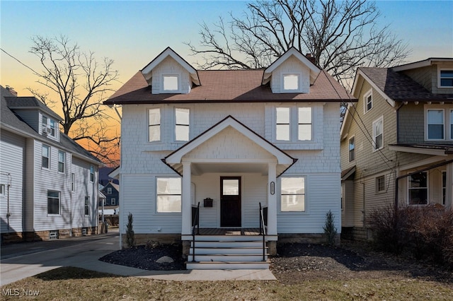 american foursquare style home with a porch and concrete driveway