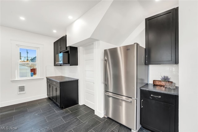 kitchen featuring visible vents, tasteful backsplash, dark countertops, and freestanding refrigerator