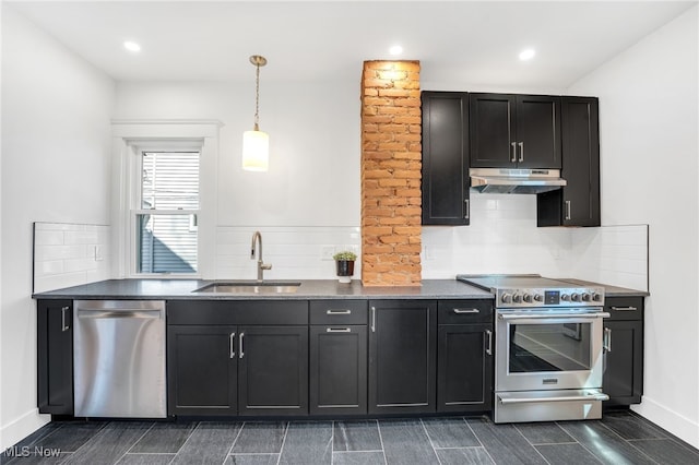 kitchen featuring a sink, under cabinet range hood, hanging light fixtures, stainless steel appliances, and dark cabinets