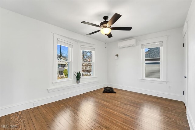 spare room featuring a ceiling fan, baseboards, wood-type flooring, and a wall mounted AC