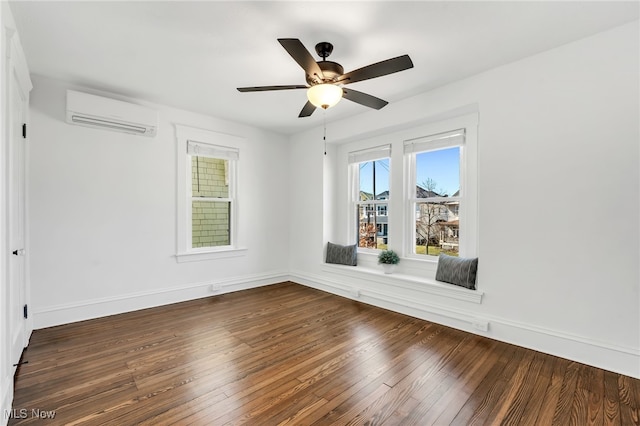 spare room with a wall mounted air conditioner, baseboards, wood-type flooring, and ceiling fan