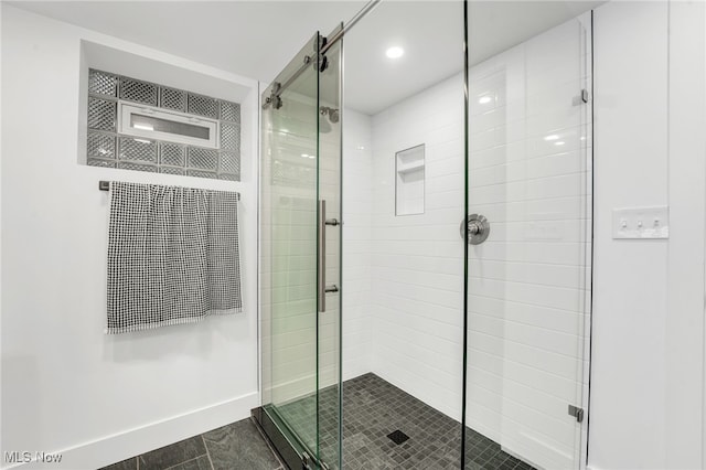 bathroom featuring a shower stall and baseboards