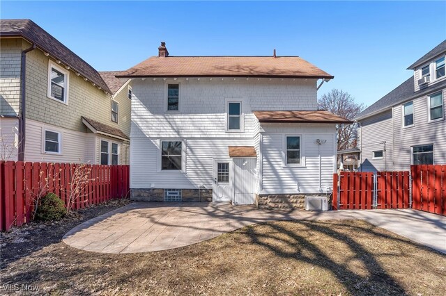 rear view of house with a patio area, a chimney, a fenced backyard, and roof with shingles