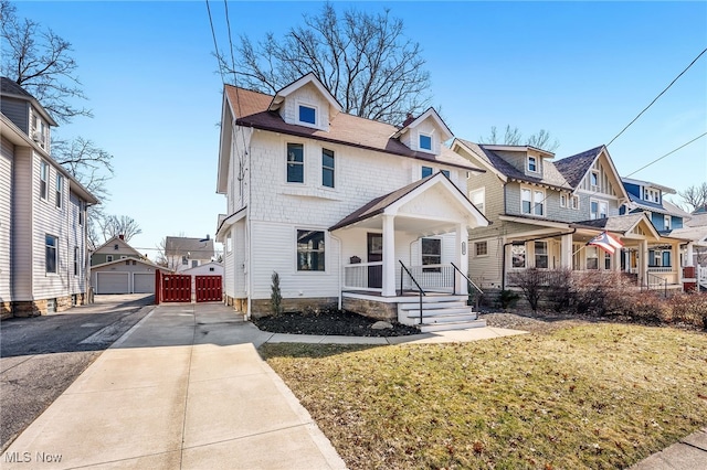 view of front of property with a detached garage, a residential view, a front yard, covered porch, and an outdoor structure