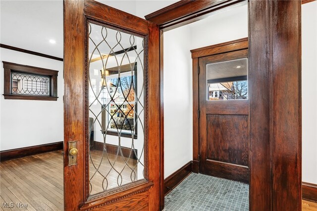 entryway with ornamental molding, baseboards, and wood finished floors