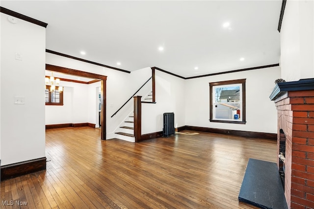 unfurnished living room with baseboards, stairway, wood-type flooring, and a brick fireplace