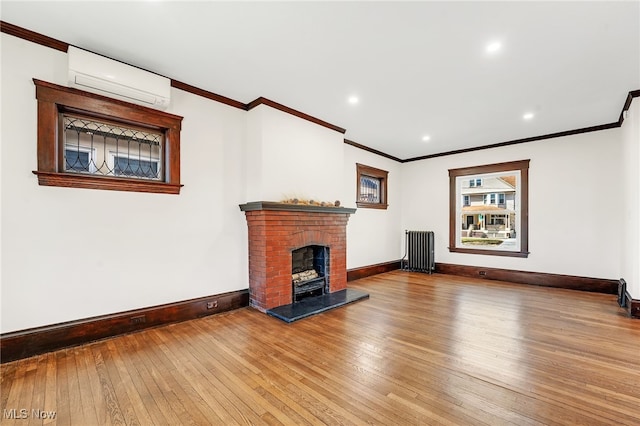 unfurnished living room with baseboards, wood-type flooring, radiator, and an AC wall unit