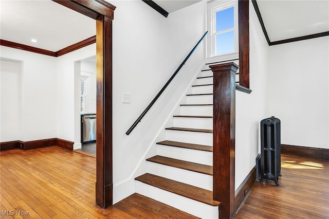 stairway featuring baseboards, ornamental molding, and hardwood / wood-style flooring