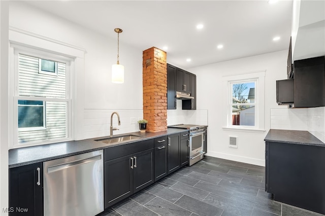 kitchen featuring dark cabinetry, under cabinet range hood, appliances with stainless steel finishes, and a sink