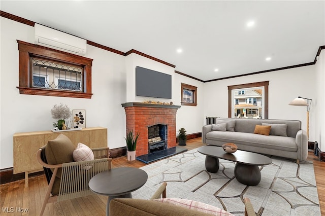 living area with ornamental molding, a wall unit AC, wood-type flooring, baseboards, and a brick fireplace