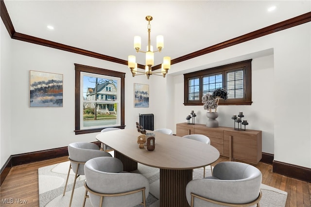 dining space with ornamental molding, hardwood / wood-style floors, radiator, baseboards, and a chandelier