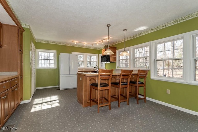 dining area with baseboards, dark carpet, and a textured ceiling