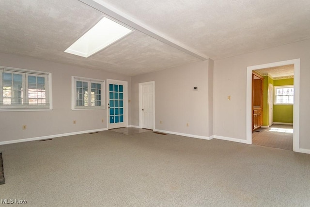 carpeted spare room featuring visible vents, baseboards, a textured ceiling, and a skylight