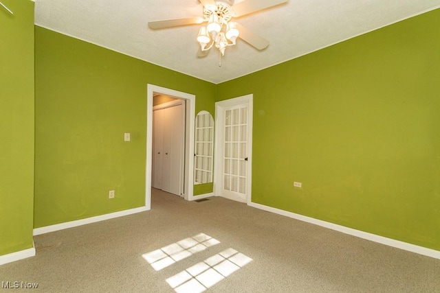 carpeted spare room with baseboards and a ceiling fan