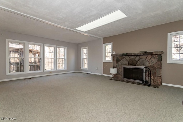 living room featuring baseboards, carpet floors, a textured ceiling, and a stone fireplace