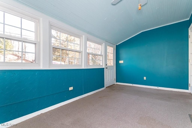 empty room with baseboards, crown molding, carpet flooring, and vaulted ceiling