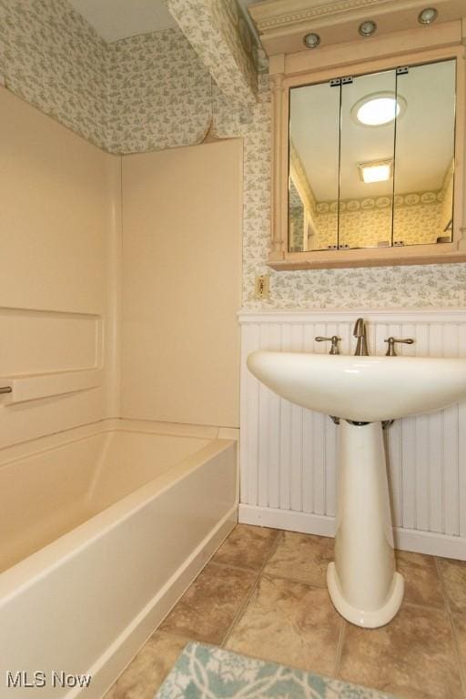 bathroom with wallpapered walls, tile patterned floors, shower / bathing tub combination, and wainscoting