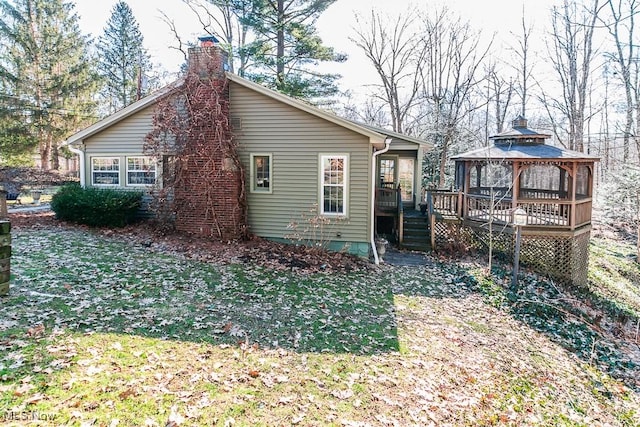 back of property with a gazebo, a chimney, and a deck