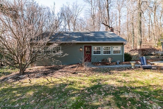 view of front of house featuring a chimney and a front yard