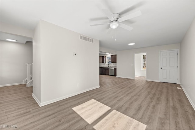 unfurnished living room featuring visible vents, light wood-style flooring, baseboards, and a ceiling fan