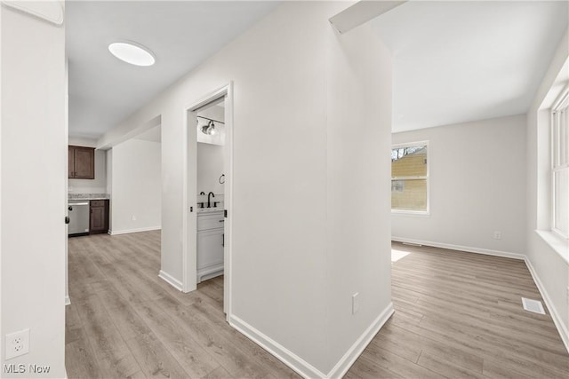 hallway with visible vents, baseboards, and light wood-style flooring